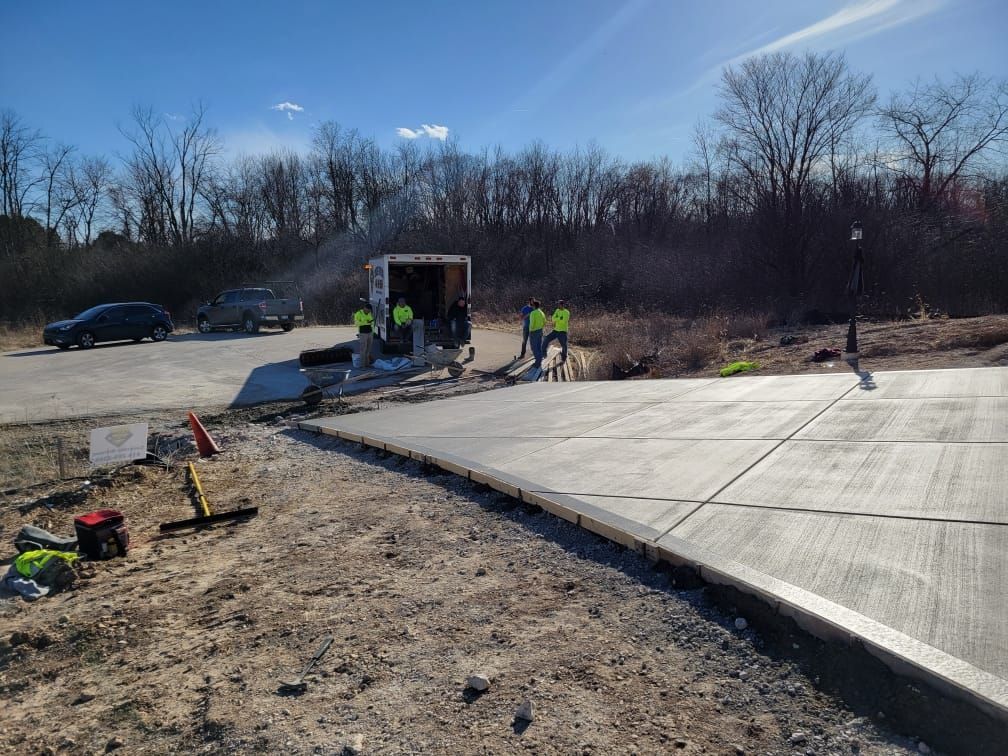 A group of construction workers are working on a concrete driveway.