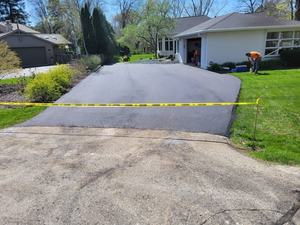 A man is working on a driveway in front of a house.