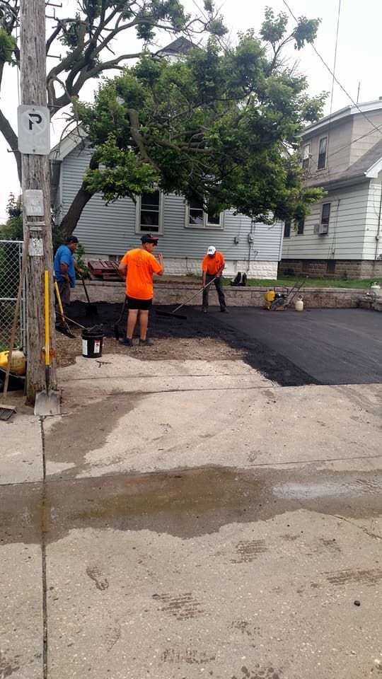 A group of men are working on a driveway in front of a house.