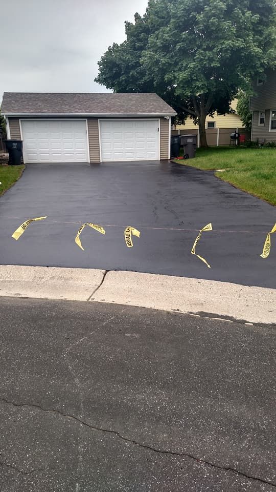 A driveway with a garage and a house in the background.