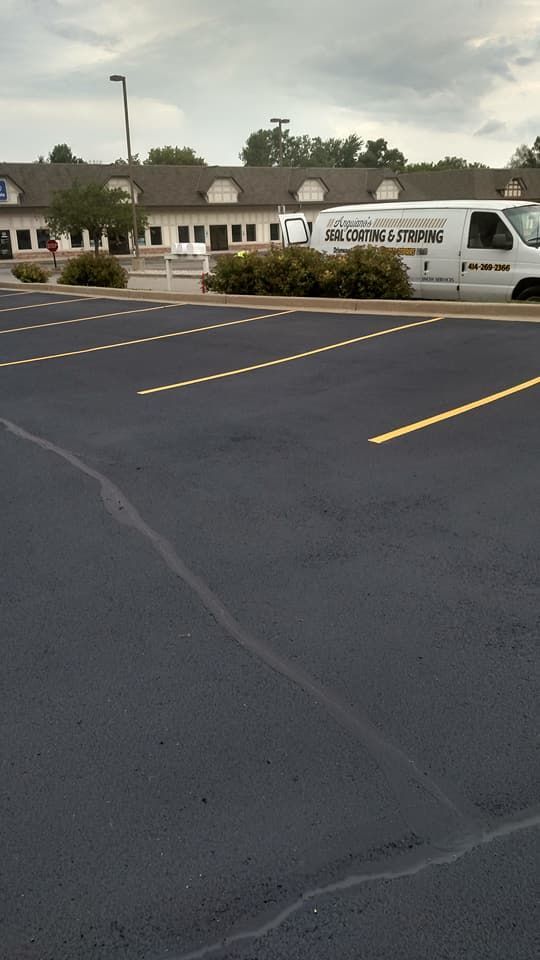 An asphalt parking lot with a van parked in front of it.