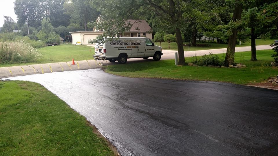 An asphalt driveway with a parked white van on the side of a road.