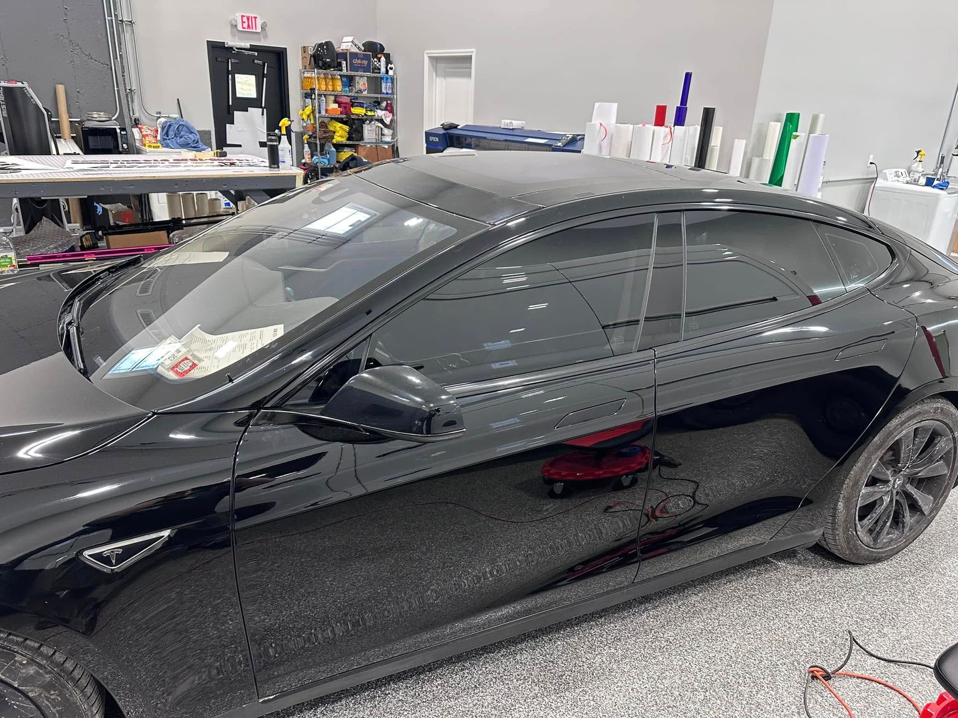 Black Tesla car with tinted windows in a workshop.