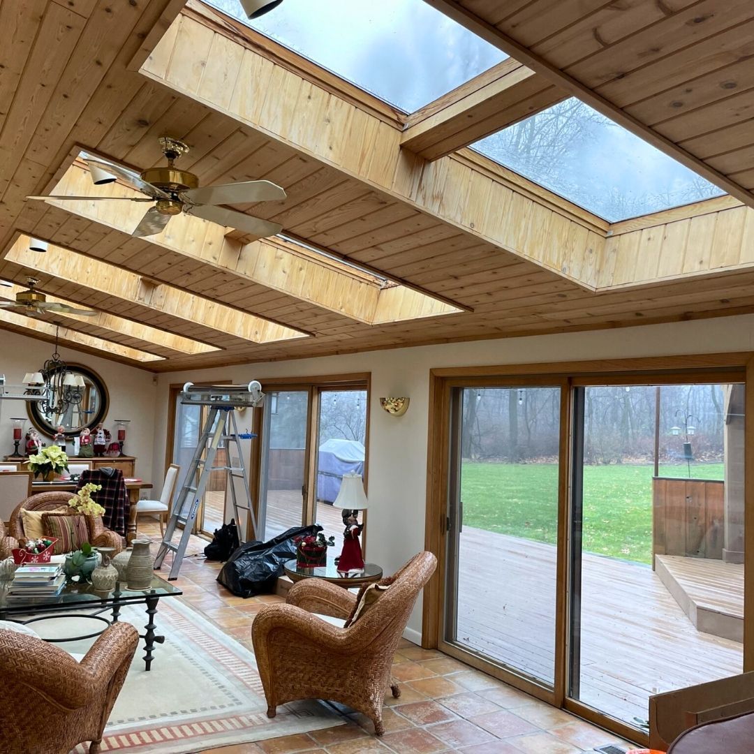 Sunroom with wood ceiling and skylights, glass sliding doors open to backyard.