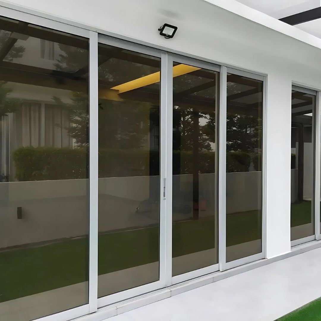 Sliding glass doors with reflective tint on a white building exterior.