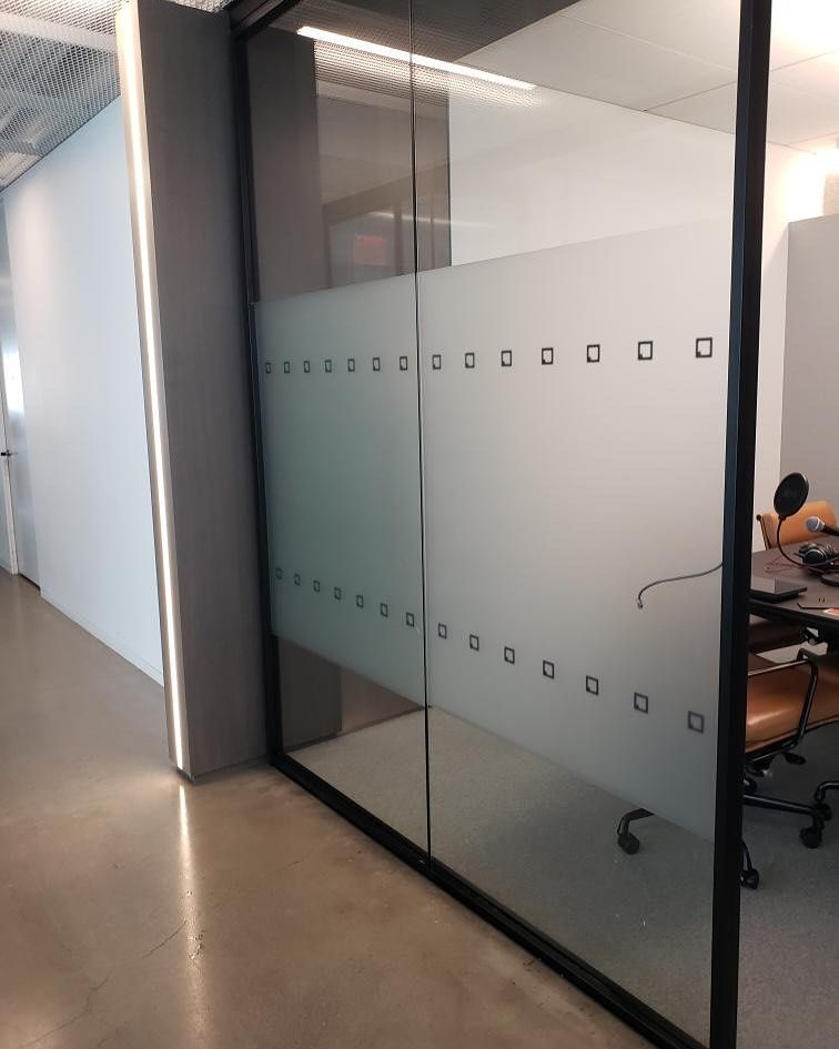 Glass office door with frosted band and square cutouts, in a modern office.