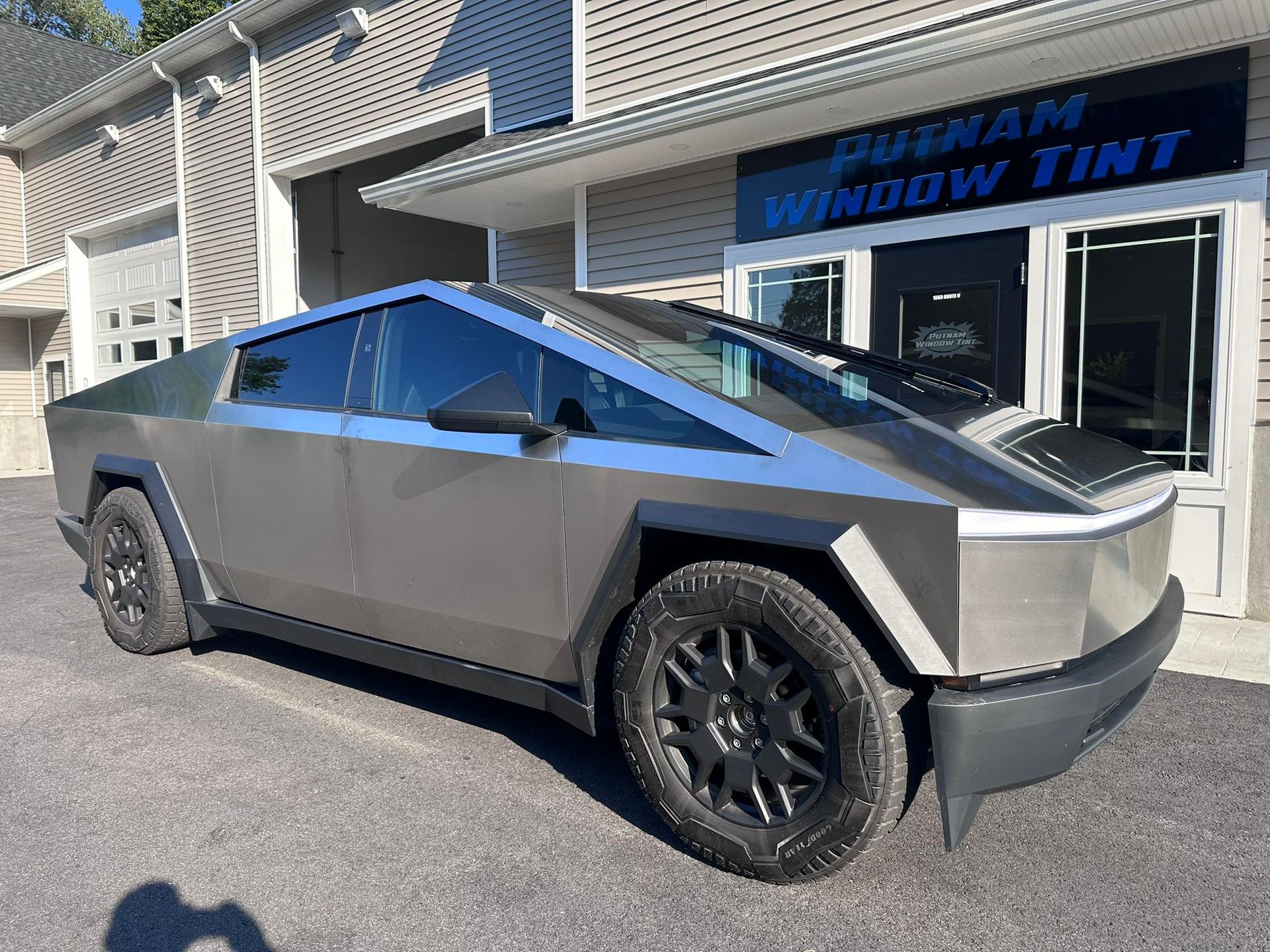 Tesla Cybertruck with tinted windows parked outside a window tinting business.