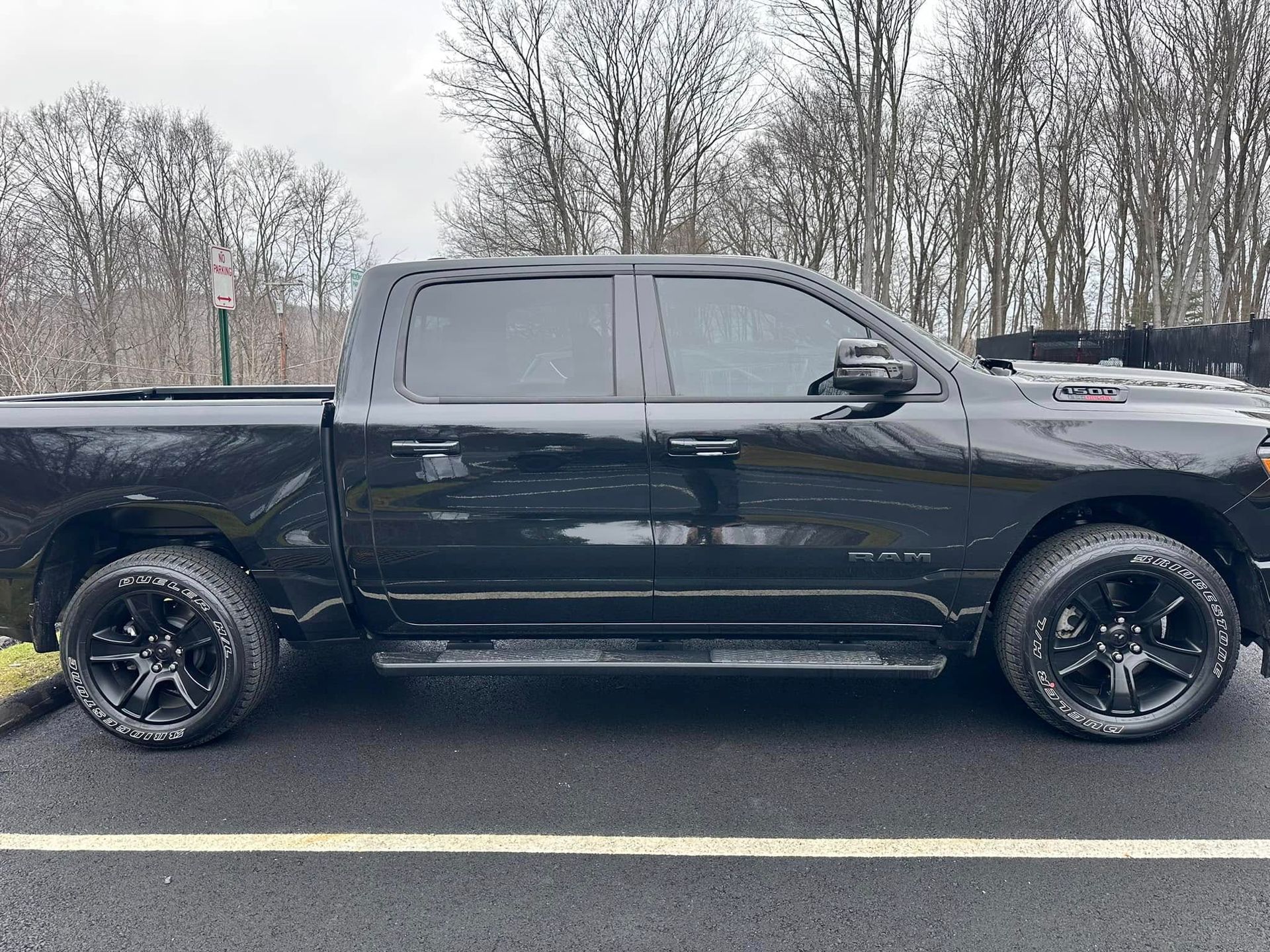 Black Ram pickup truck parked on asphalt, cloudy day.