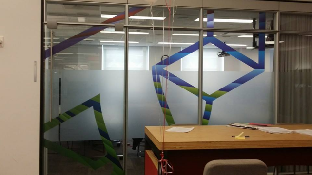 Office interior with frosted glass wall, geometric design, and desk.
