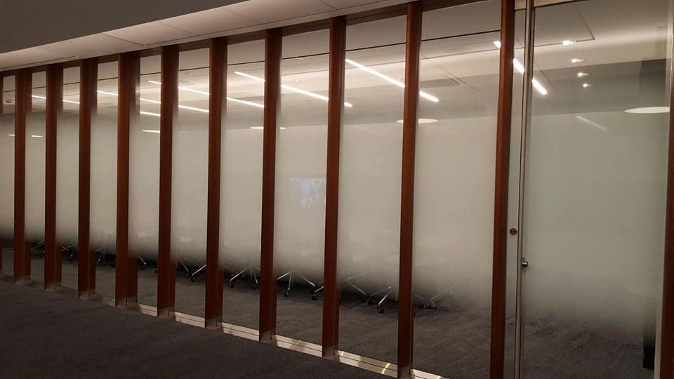 Wooden slats and frosted glass wall in a modern office, partially obscuring a seating area.
