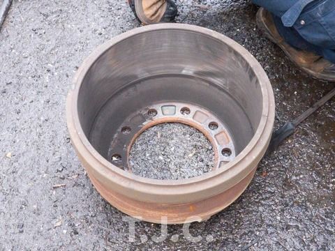 Rust-colored metal wheel rim on gravel with a person’s boot visible nearby