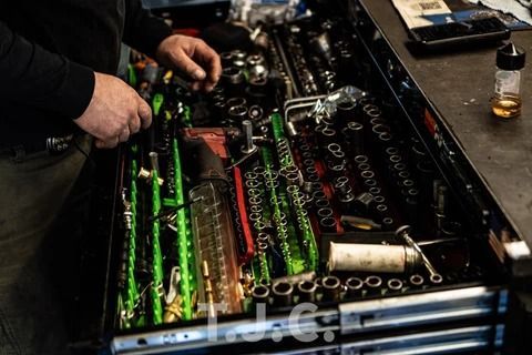 Mechanic working on a car engine with glowing green and red components in a workshop