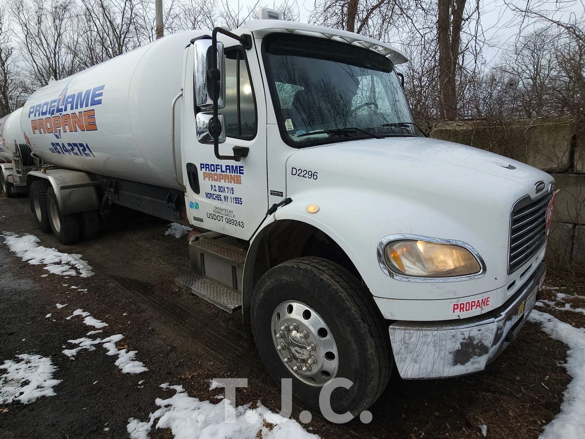 White tanker truck on a muddy roadside, viewed from the front-left side.