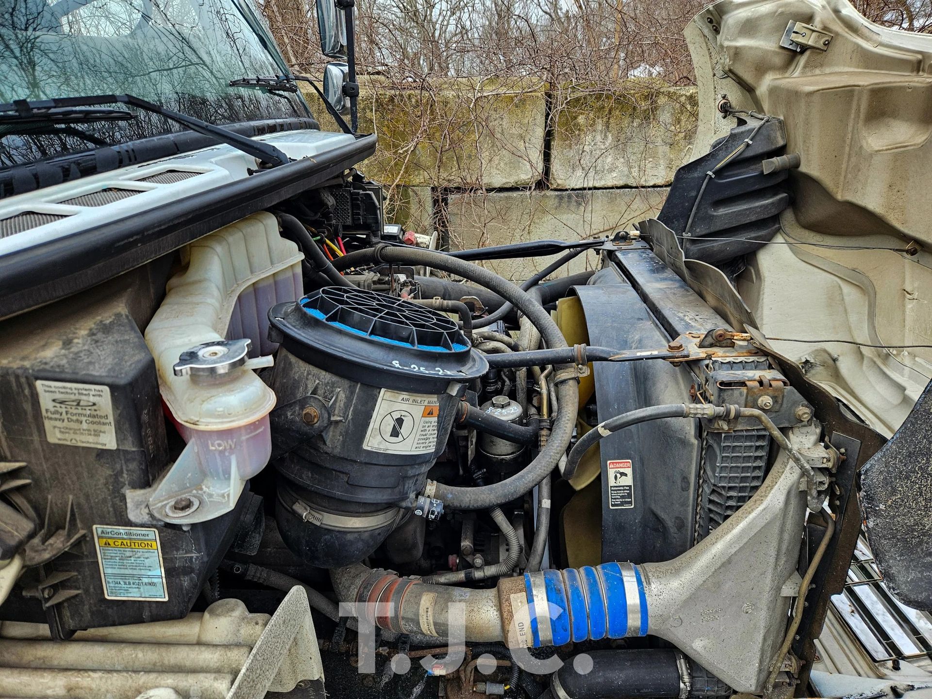 Open car engine bay with hoses, air intake, and dusty components visible.