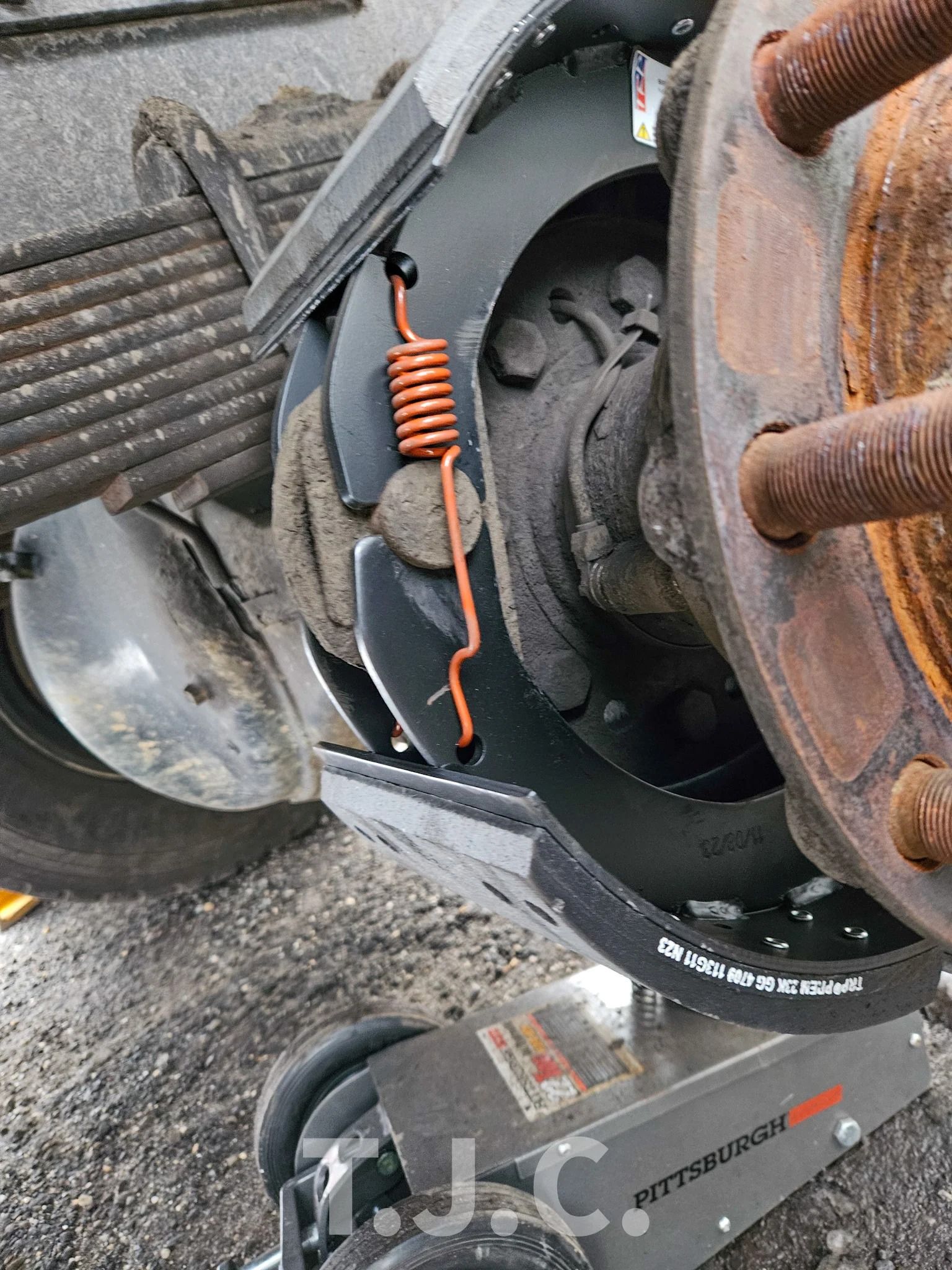 Close-up of rusted farm machinery wheel hub with spring and bolts