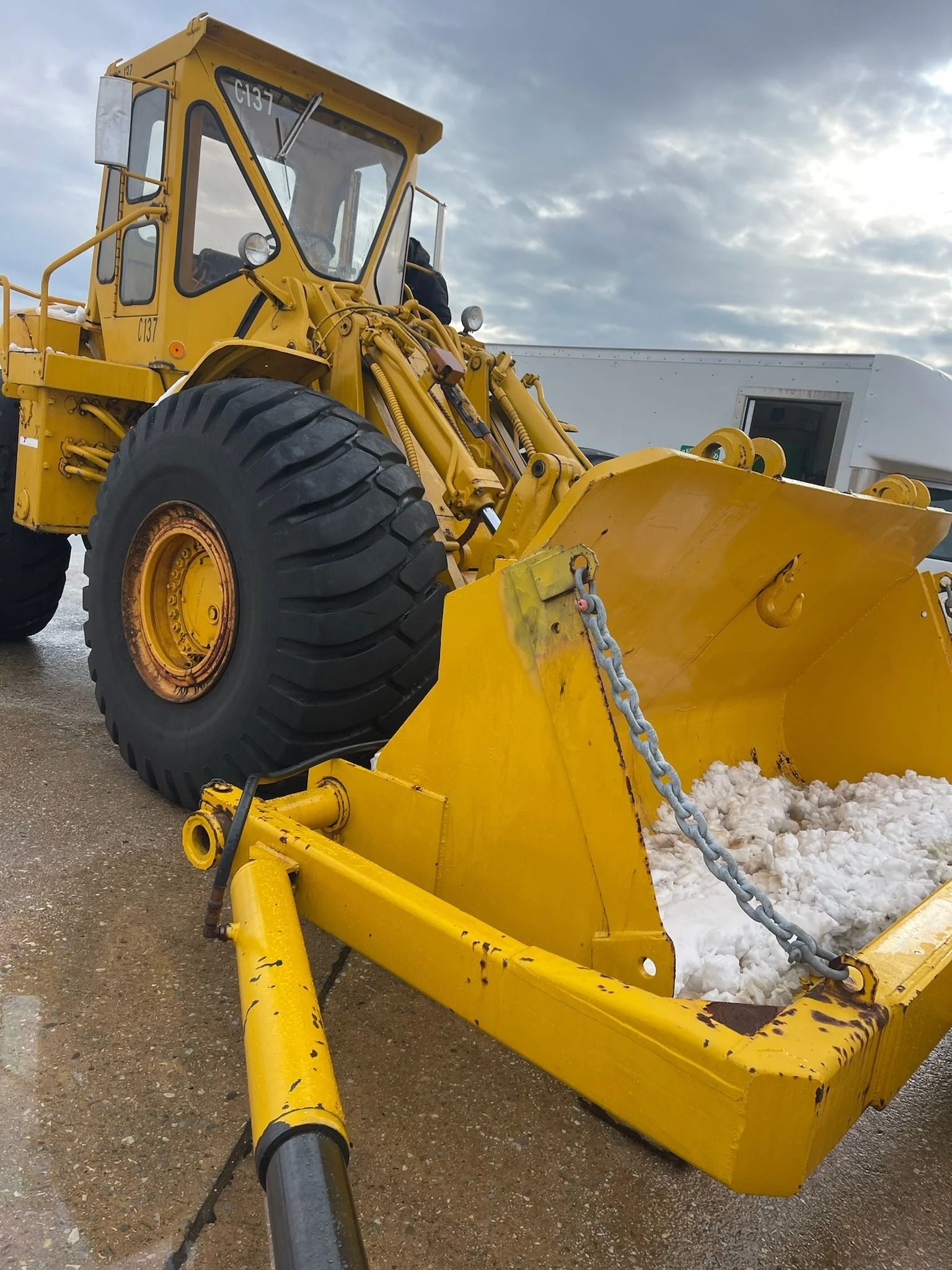 Yellow front loader with a snow pusher attachment clearing snow in an outdoor lot
