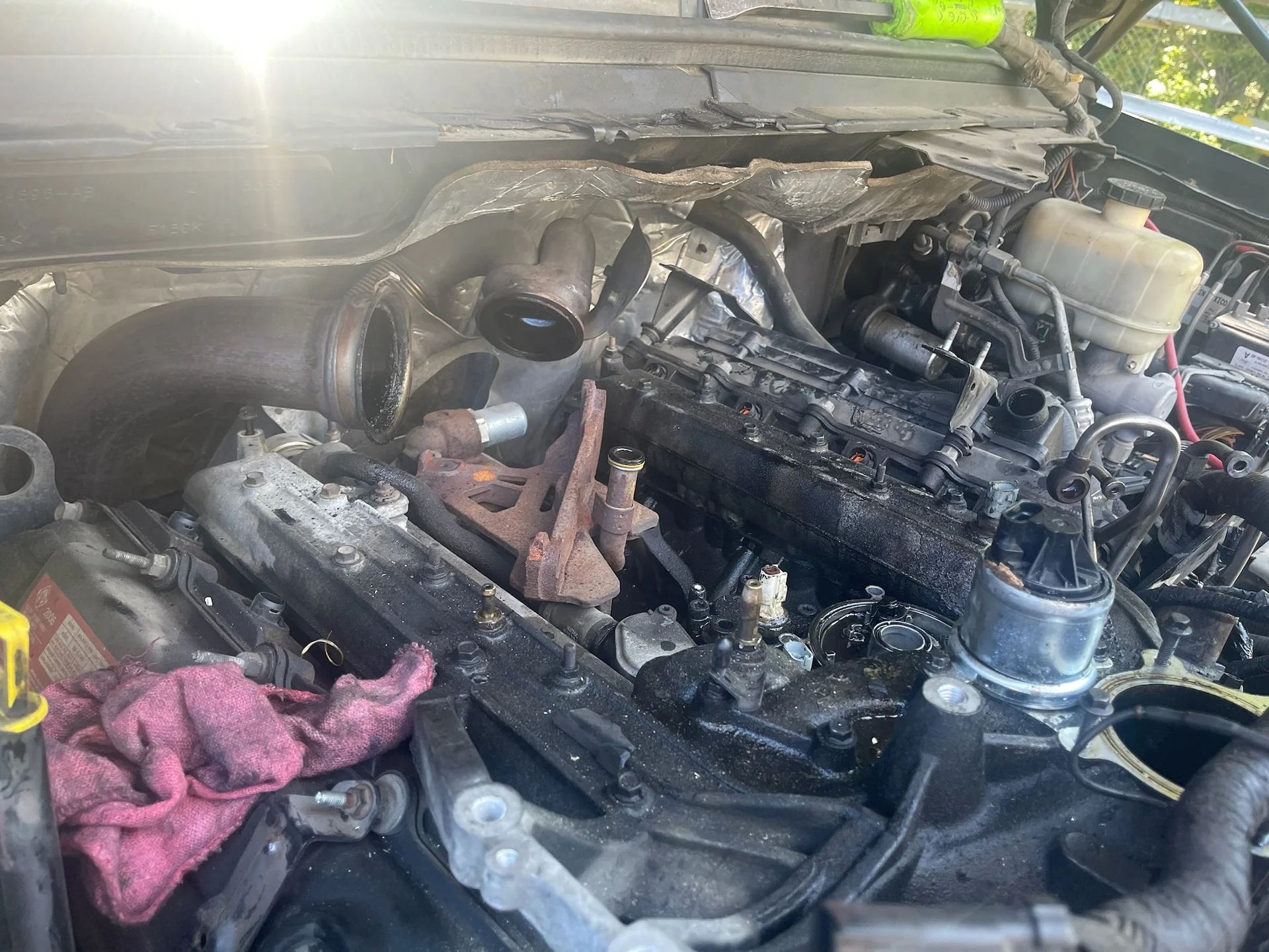 Burned car engine bay with charred parts, smoke damage, and a pink cloth in the foreground