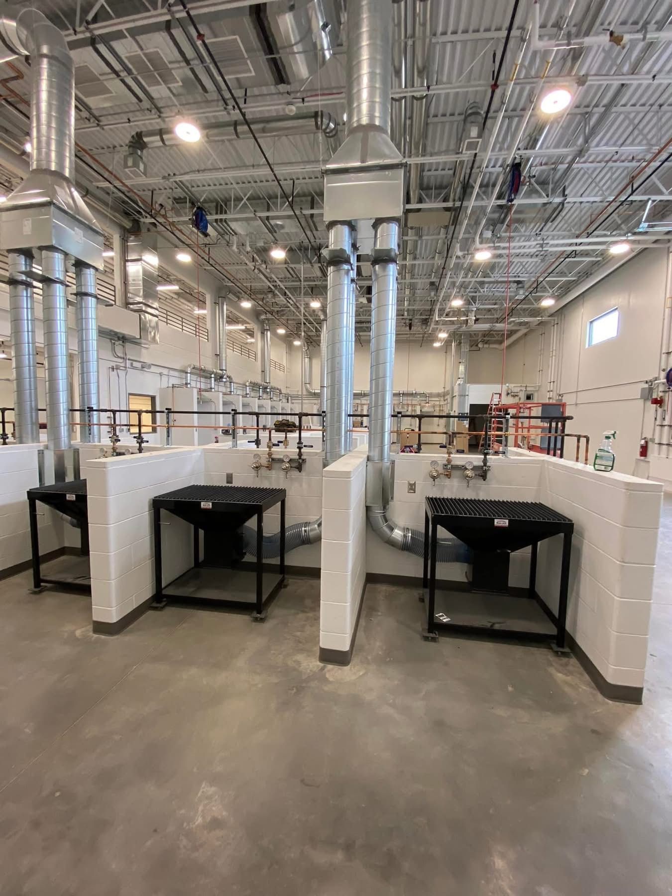 A large room with a lot of pipes and tables in it.