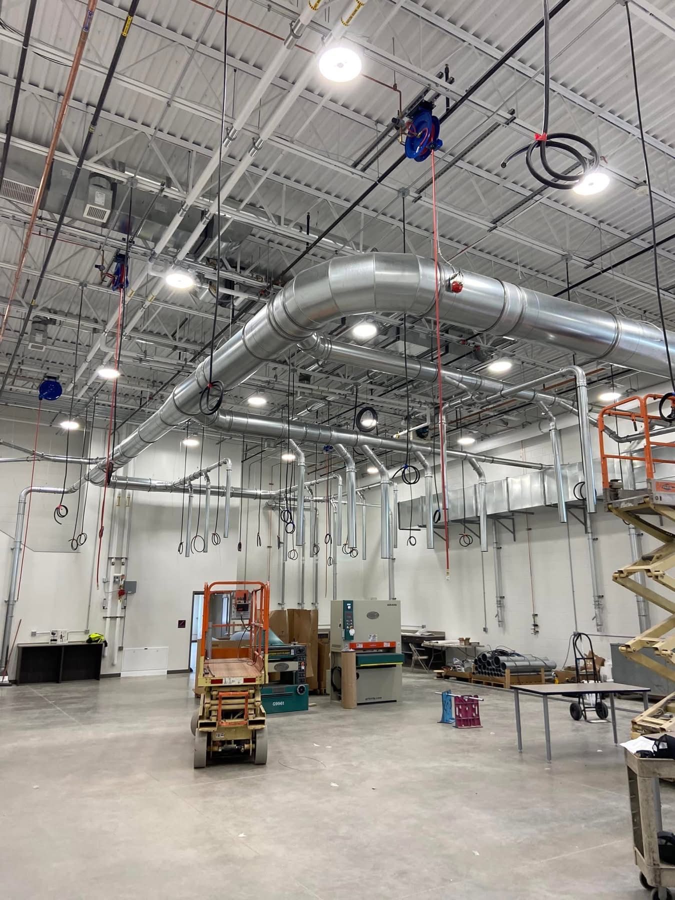 A large warehouse with a lot of pipes hanging from the ceiling.