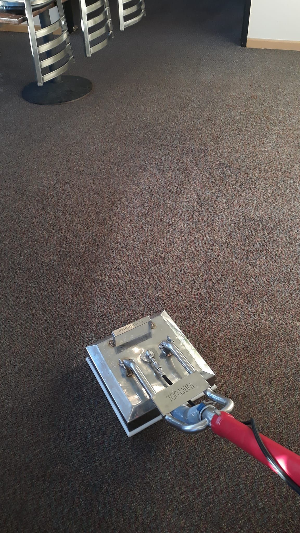 A vacuum cleaner is being used to clean a carpet in a room.