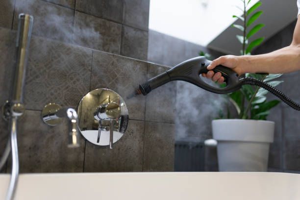 A person is cleaning a bathtub with a steam cleaner.