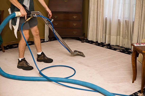 A man is using a vacuum cleaner to clean a carpet in a living room.