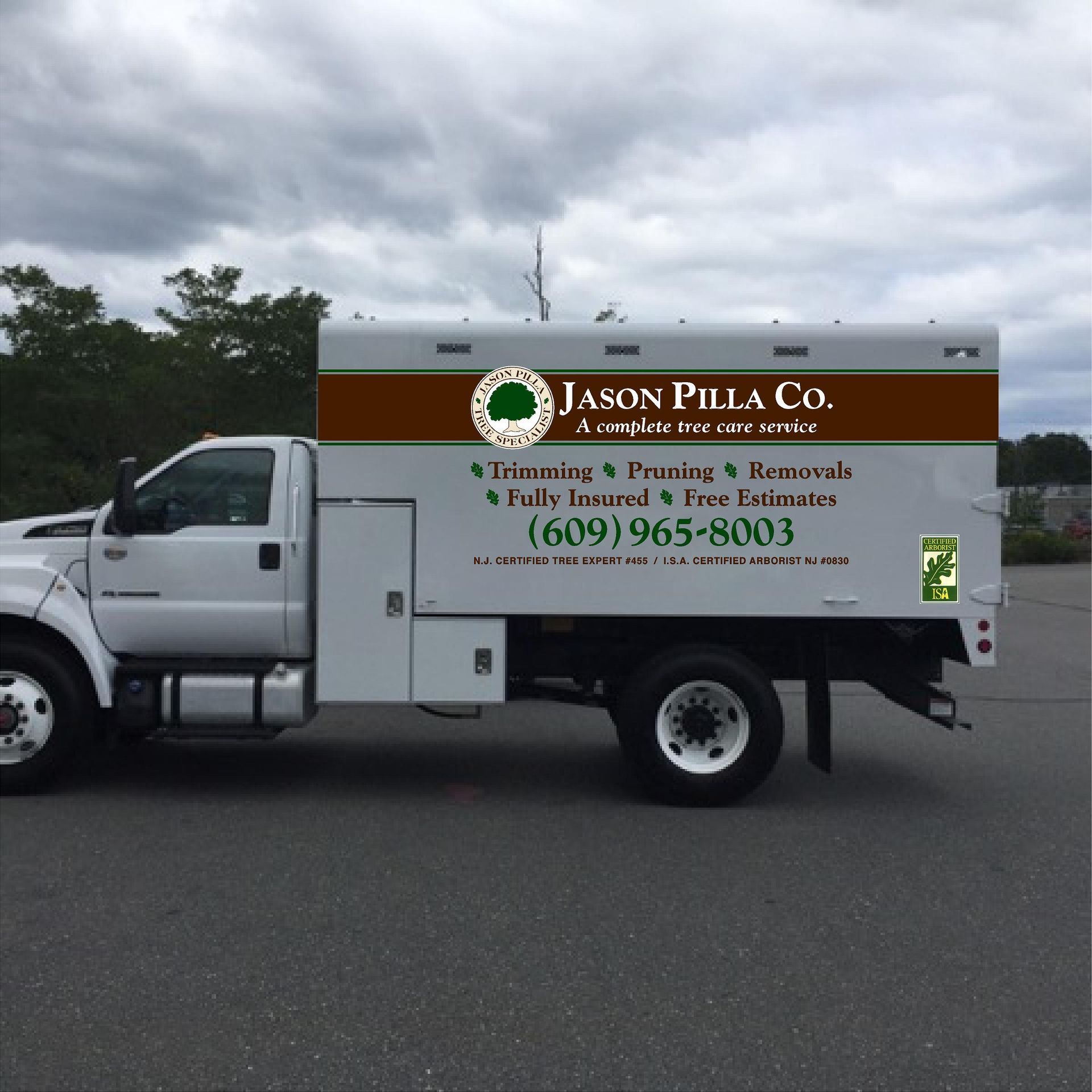 White Jason Pilla Co. landscaping truck parked on asphalt. Advertisement features company logo, services, and phone number.