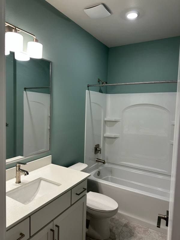 Bathroom with teal walls, white fixtures, vanity, and bathtub.