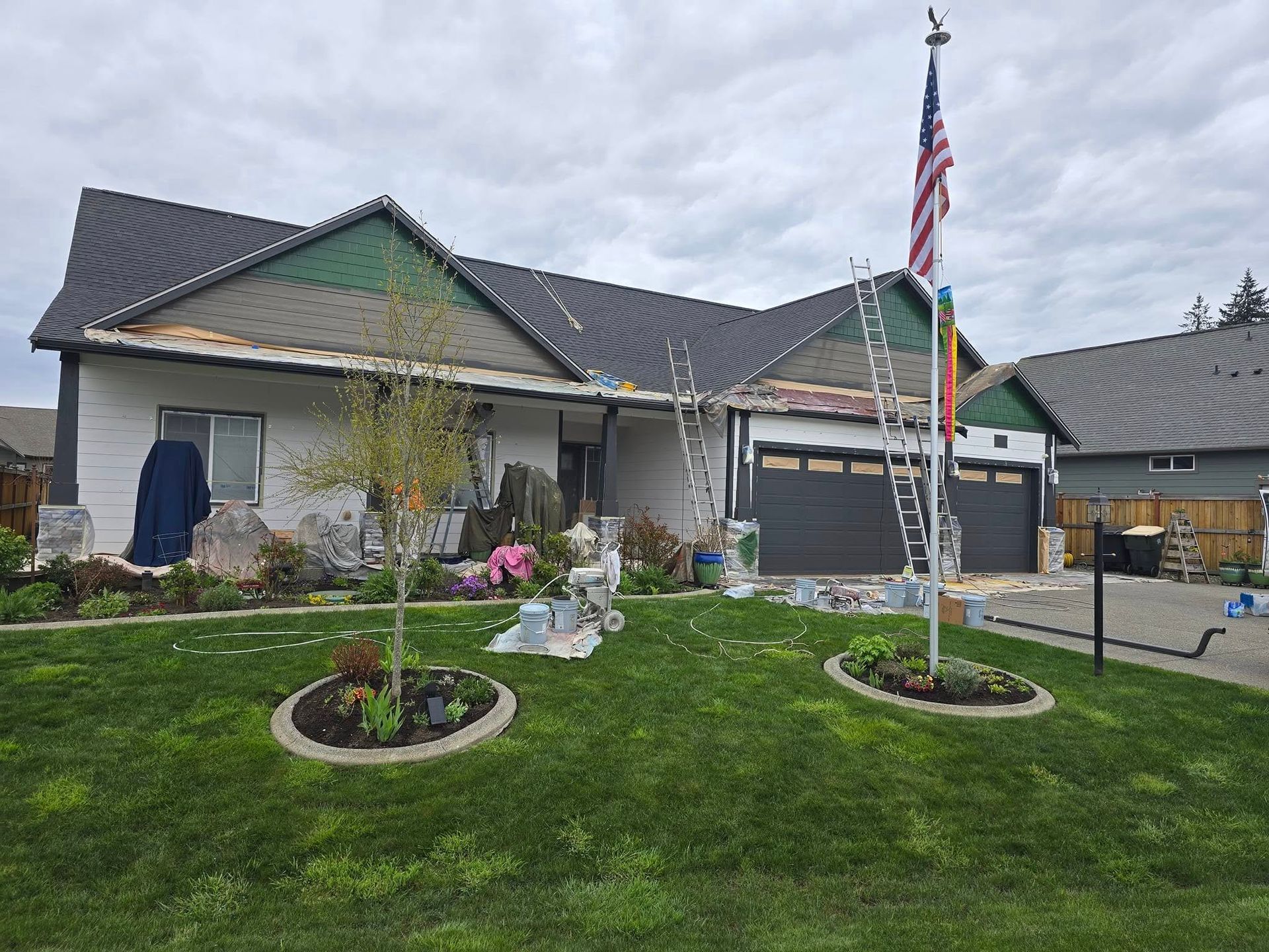 House undergoing roof and siding work with an American flag.