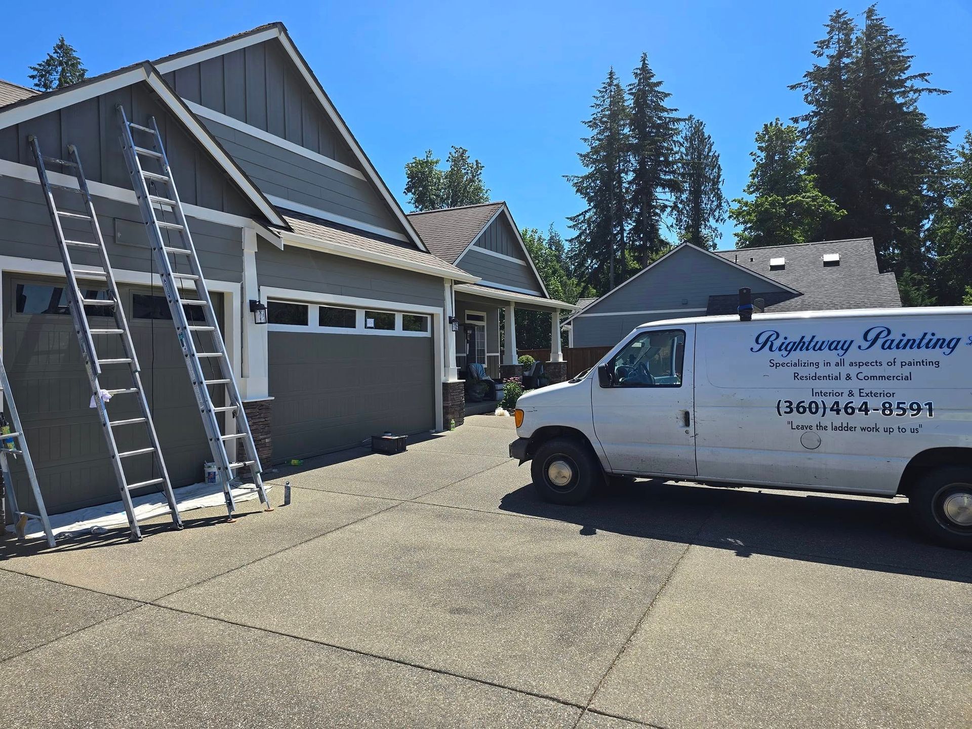 Ladders leaned against a house being painted by a white 