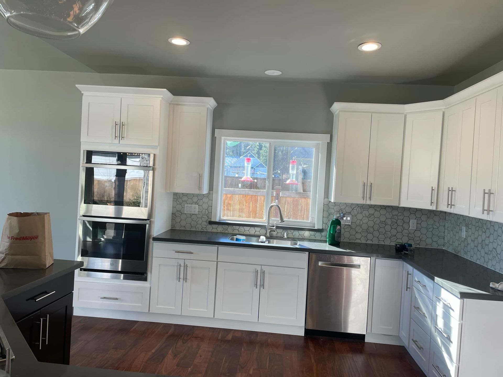 White kitchen cabinets with black countertops and stainless steel appliances.
