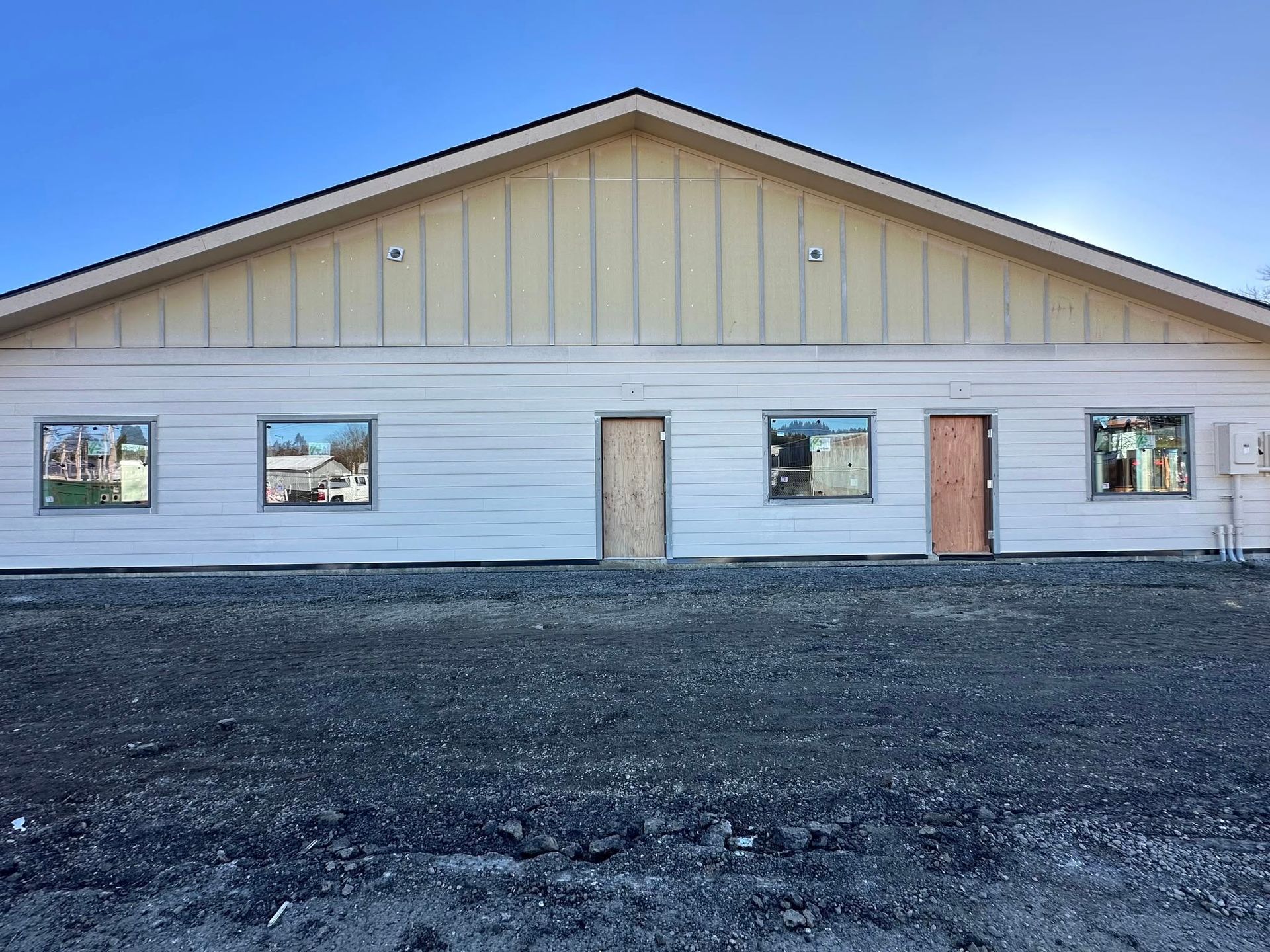 Exterior view of a light yellow building with windows and doors, set against a blue sky.