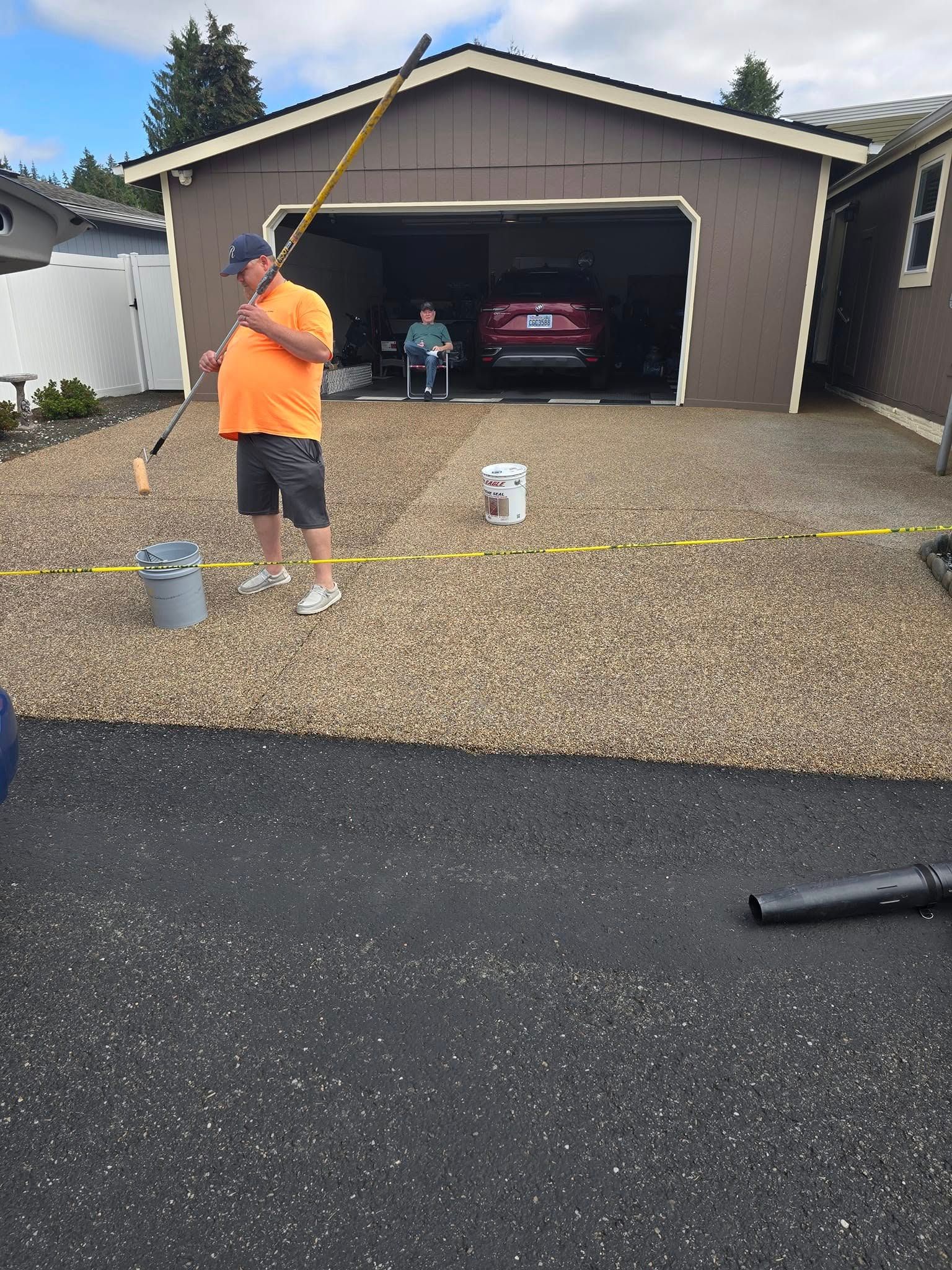 Man in orange shirt working on a gravel driveway next to a garage, a car inside.