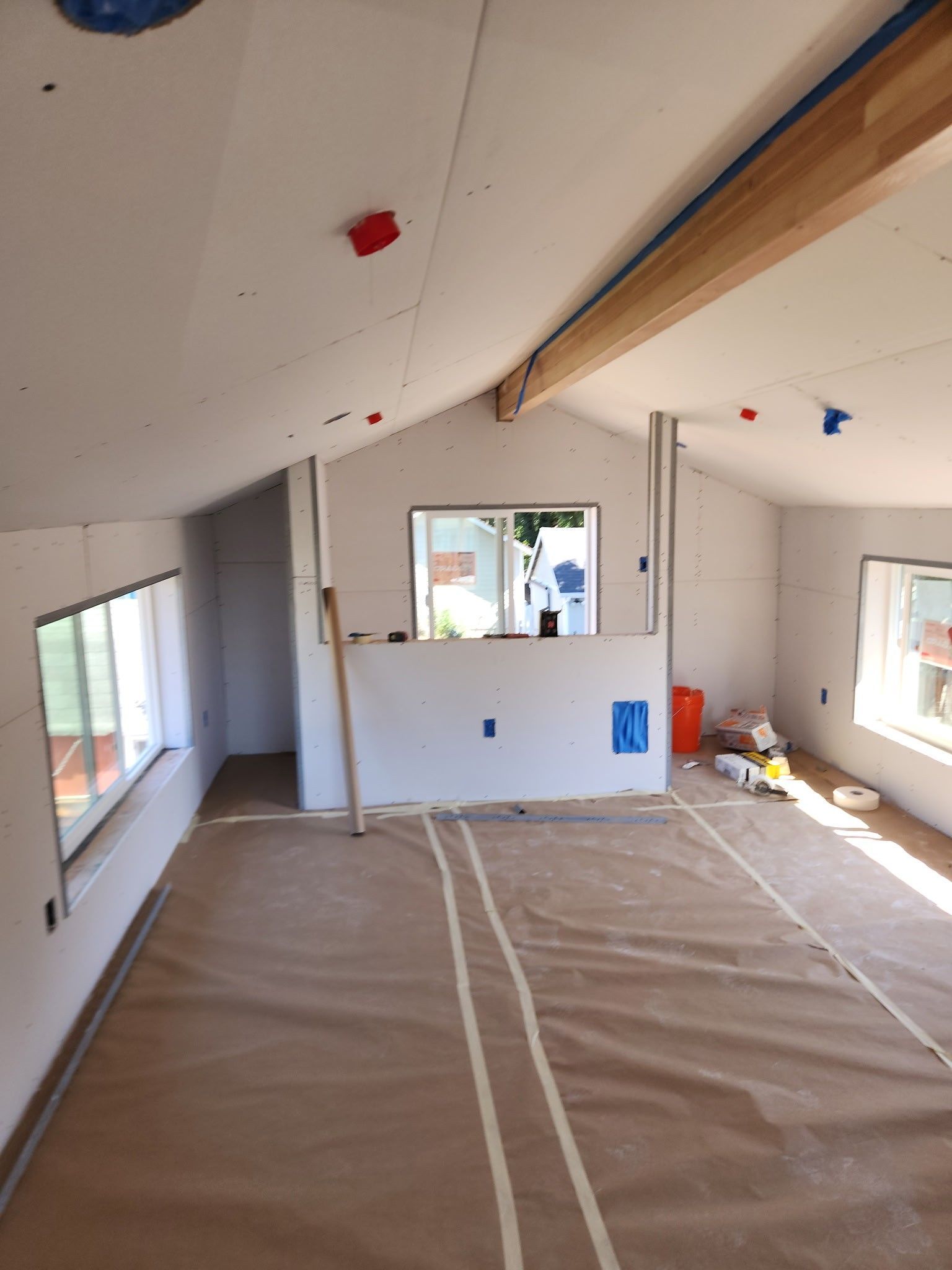Interior construction, drywall walls, high ceiling, windows, and protective floor covering.