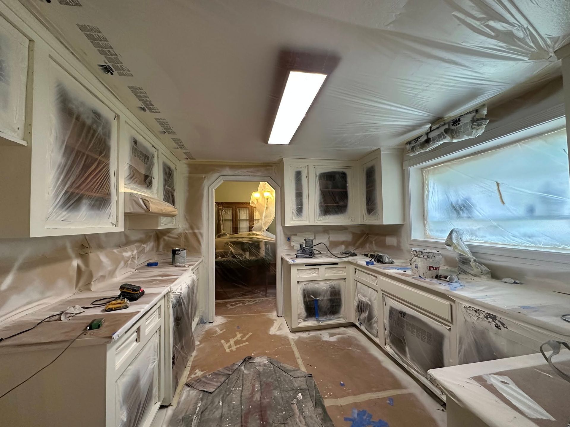 Kitchen cabinets and surfaces covered in plastic for painting. Interior shot.