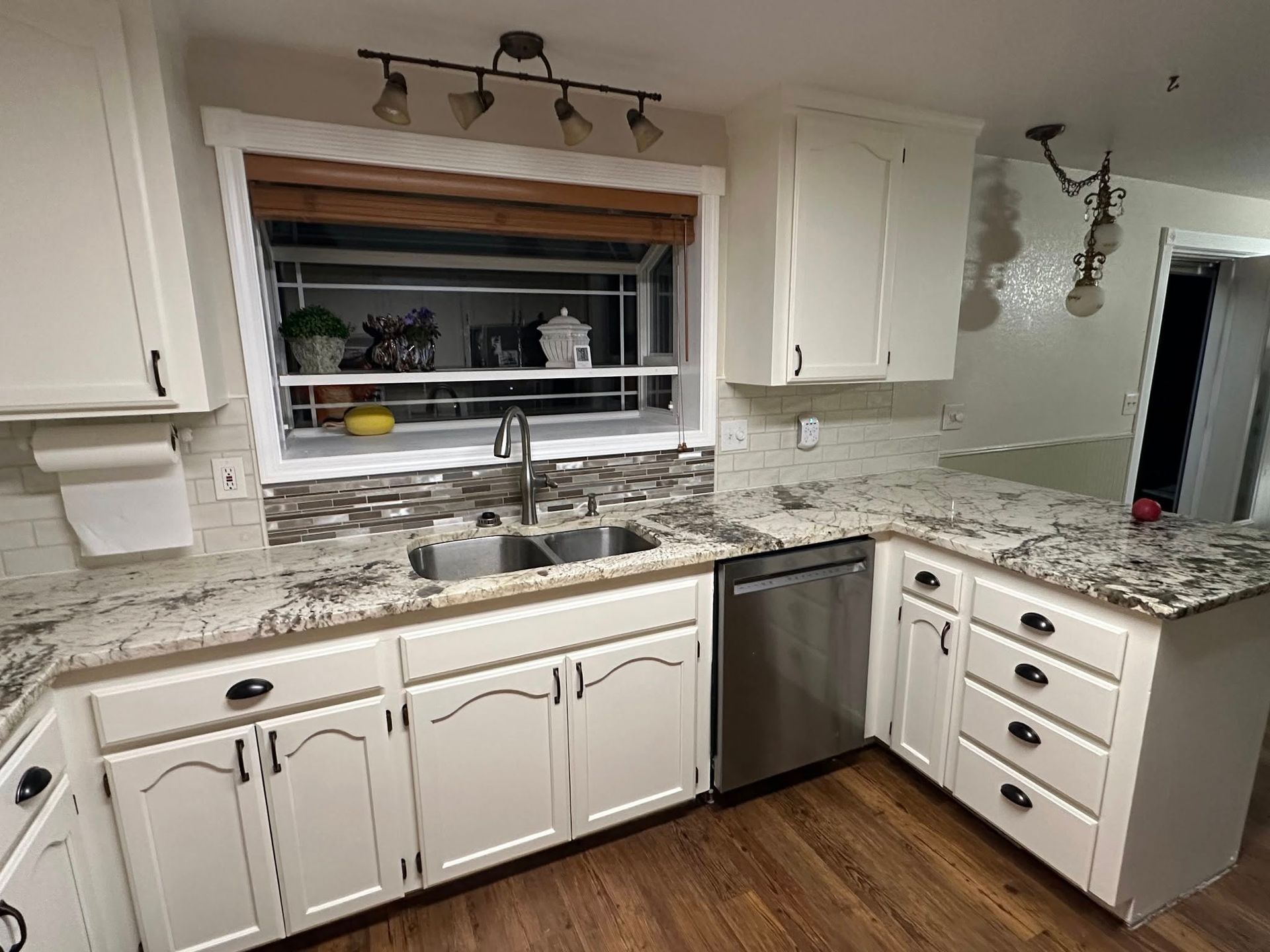 Cream kitchen with granite countertops, stainless steel appliances, and a window.