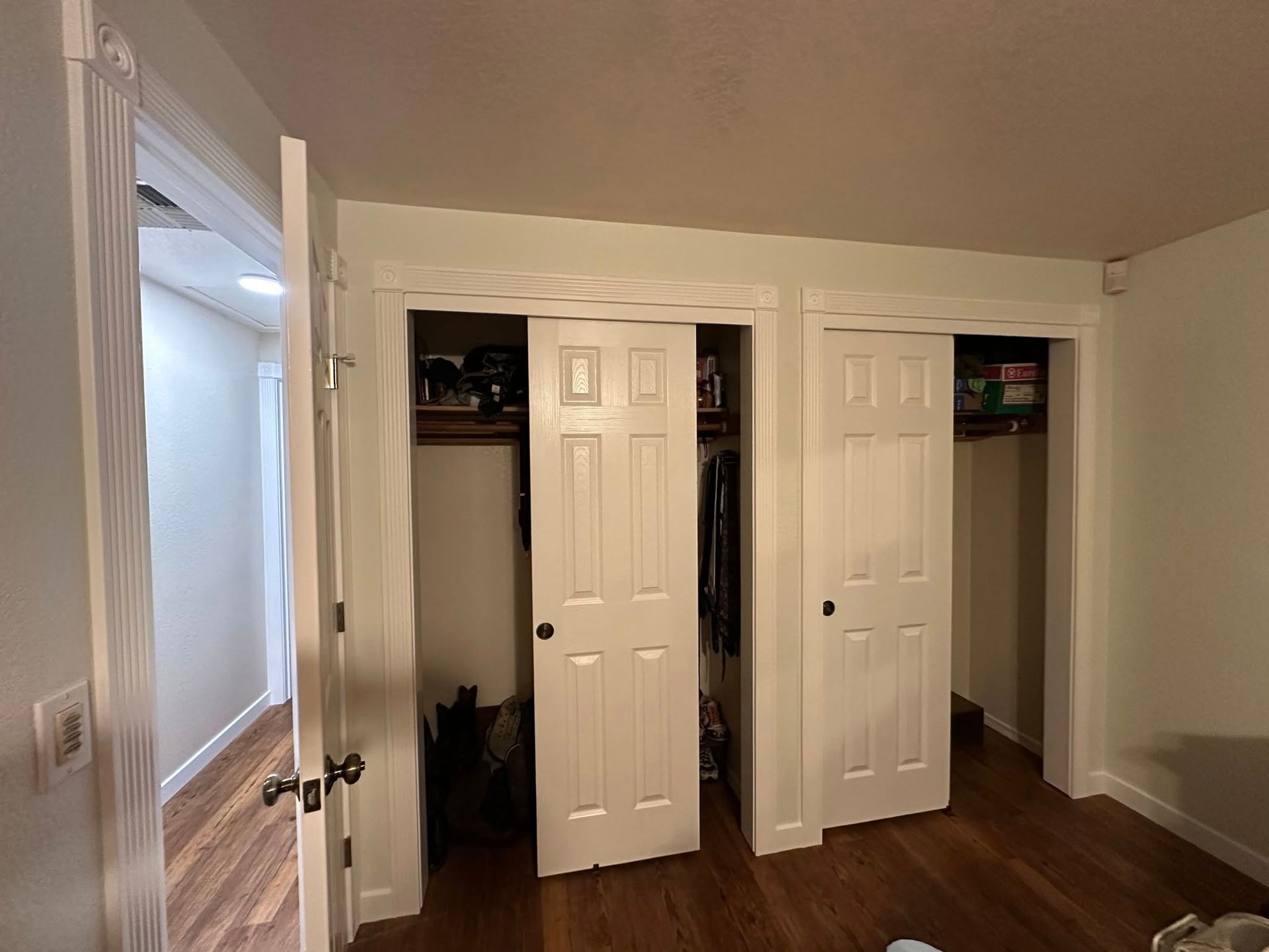 Bedroom with two white sliding closet doors; hallway door open on the left.