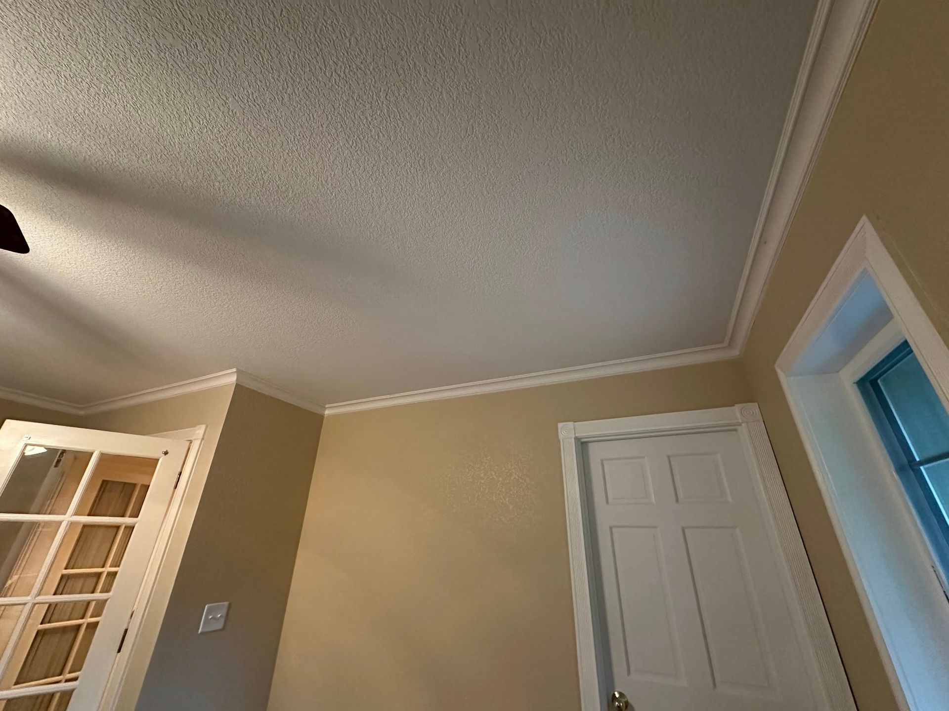 Room interior with textured ceiling, crown molding, and a closed white door.