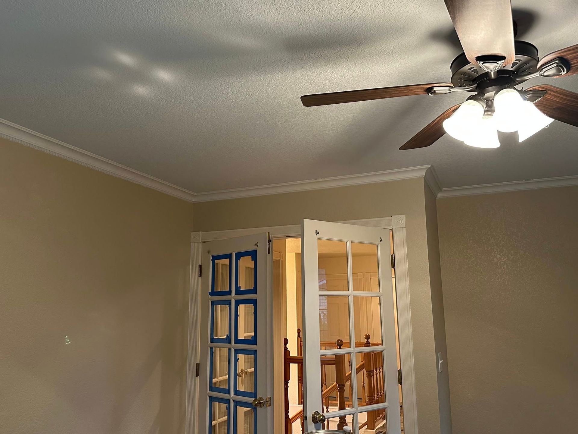 Ceiling fan and open French doors in a room with light-colored walls and white trim.