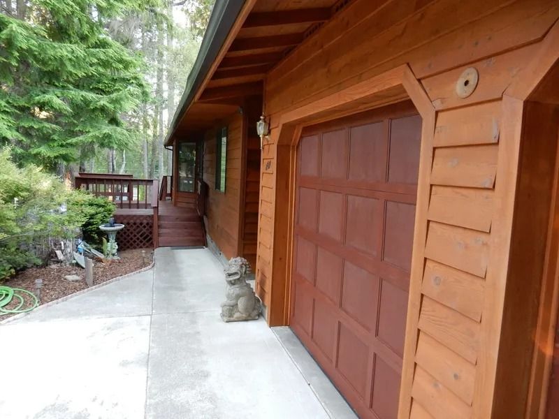 Brown wooden garage door and house exterior with a walkway and deck.
