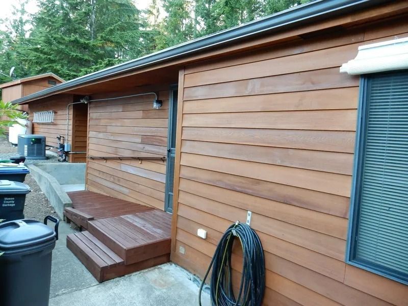 Brown wooden building with dark steps and ramp, door, window, hose.