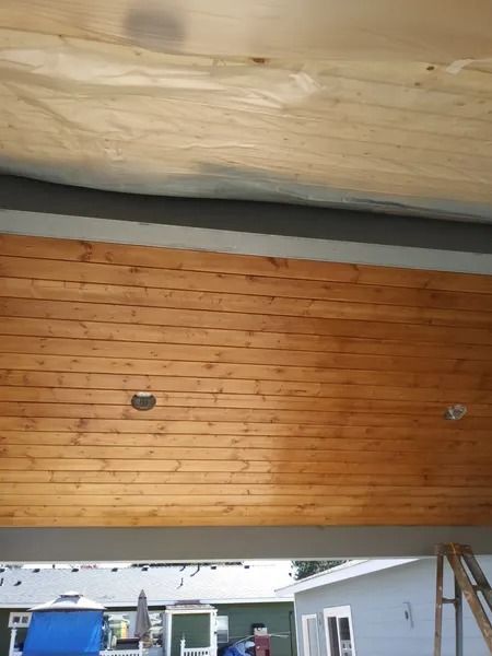 Wooden plank ceiling with two circular cutouts, gray beam, and outdoor scene.