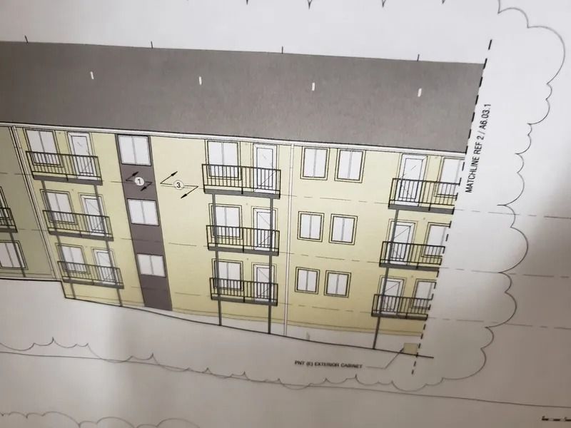 Architectural rendering of a tan apartment building with brown trim, balconies, and a gray roof.