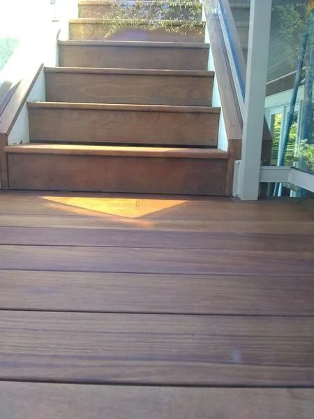 Wooden stairs leading upwards, lit by sunlight. Wooden deck in foreground.