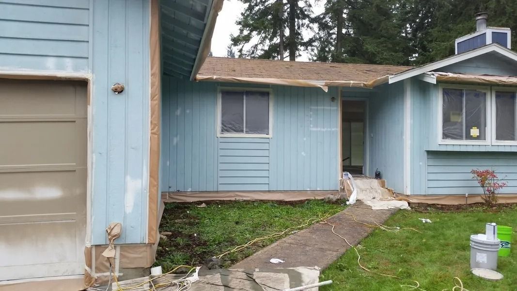 Blue house exterior with a garage and entry, undergoing renovations.