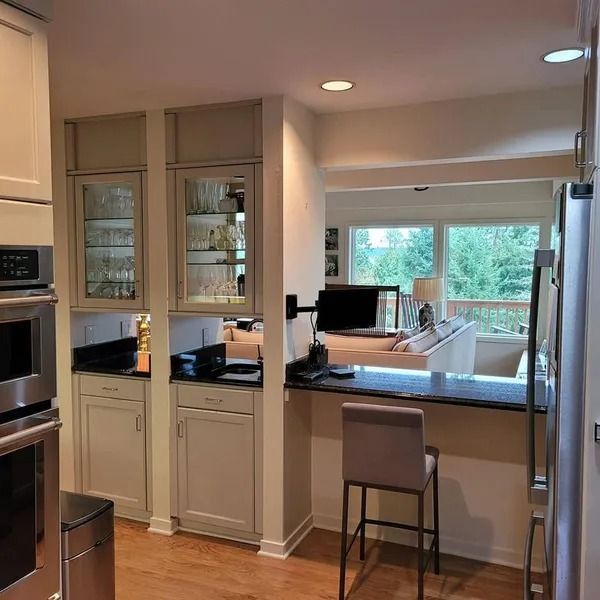 Kitchen with built-in cabinetry, bar seating, and a view of a living room with sofa.