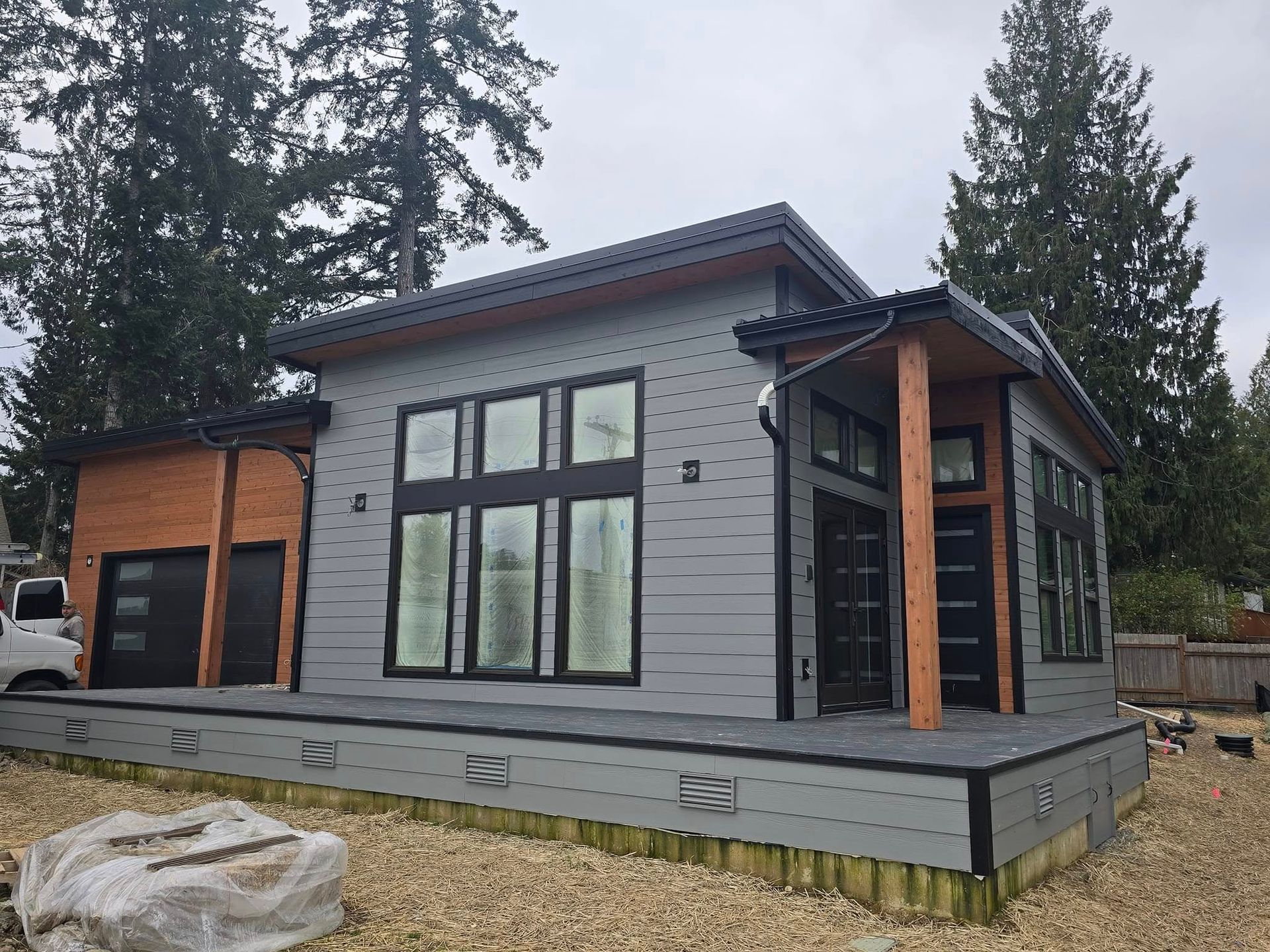 Modern gray house with black trim, large windows, and a wooden porch.