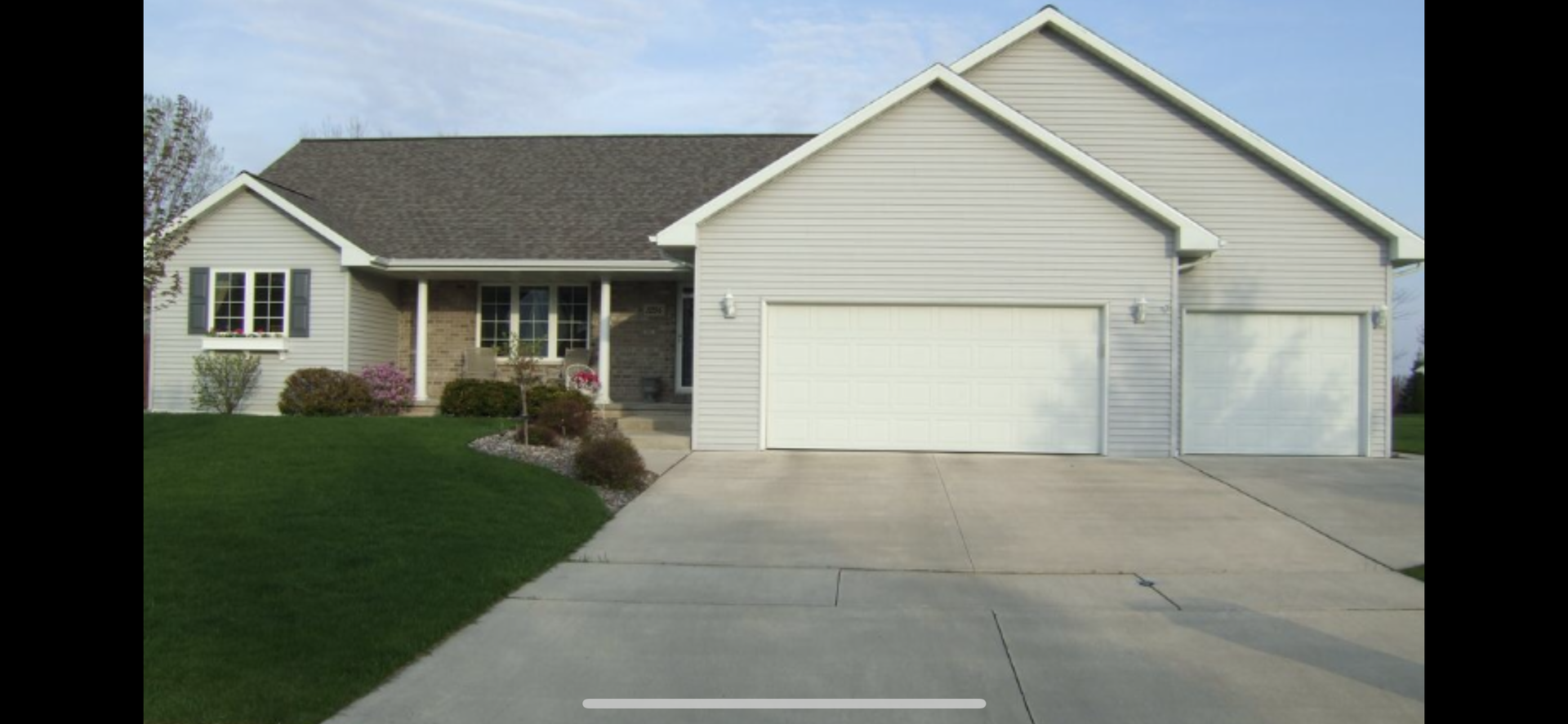 A white house with two garage doors and a concrete driveway.