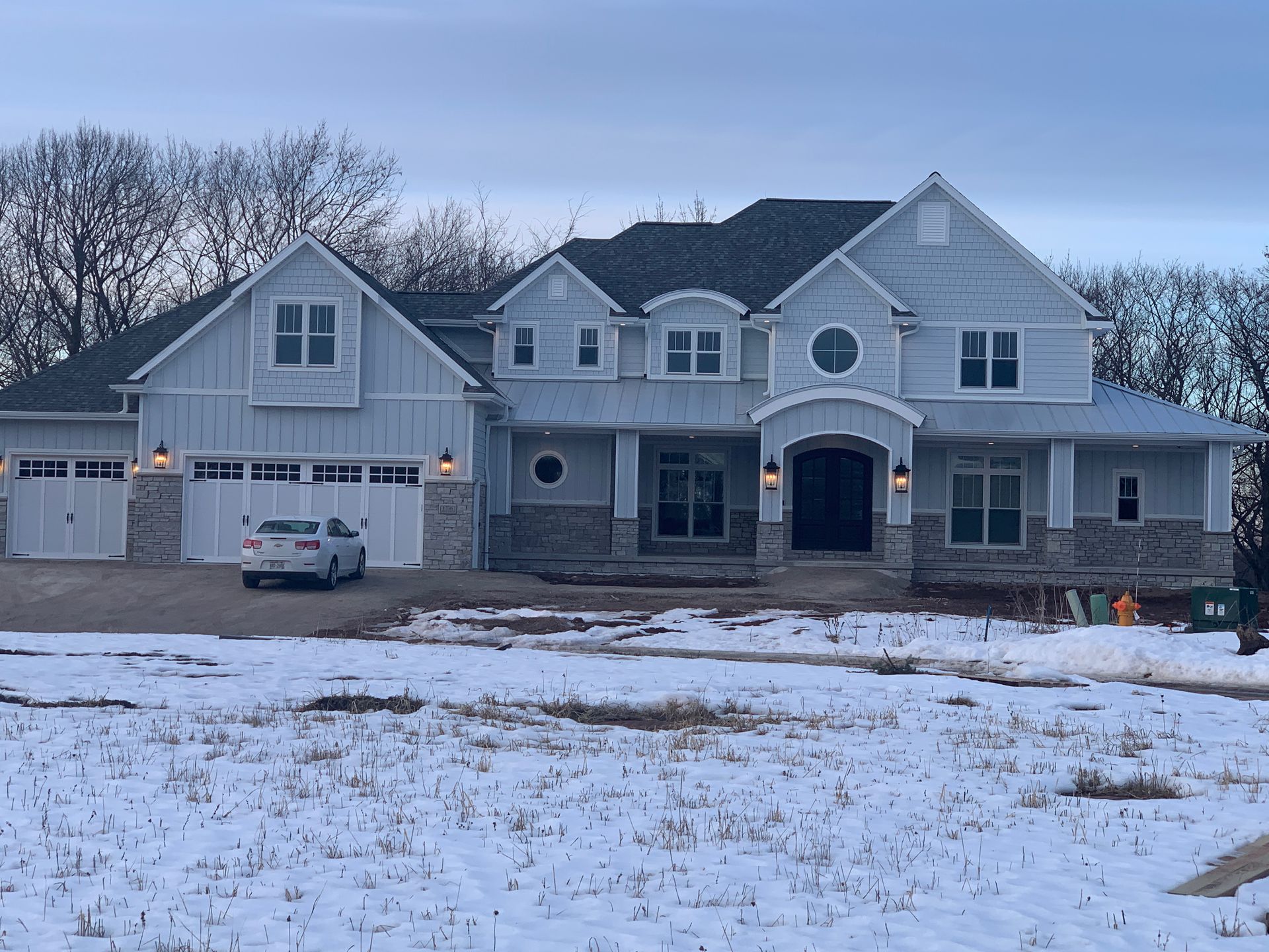 A large white house is sitting in the middle of a snowy field.