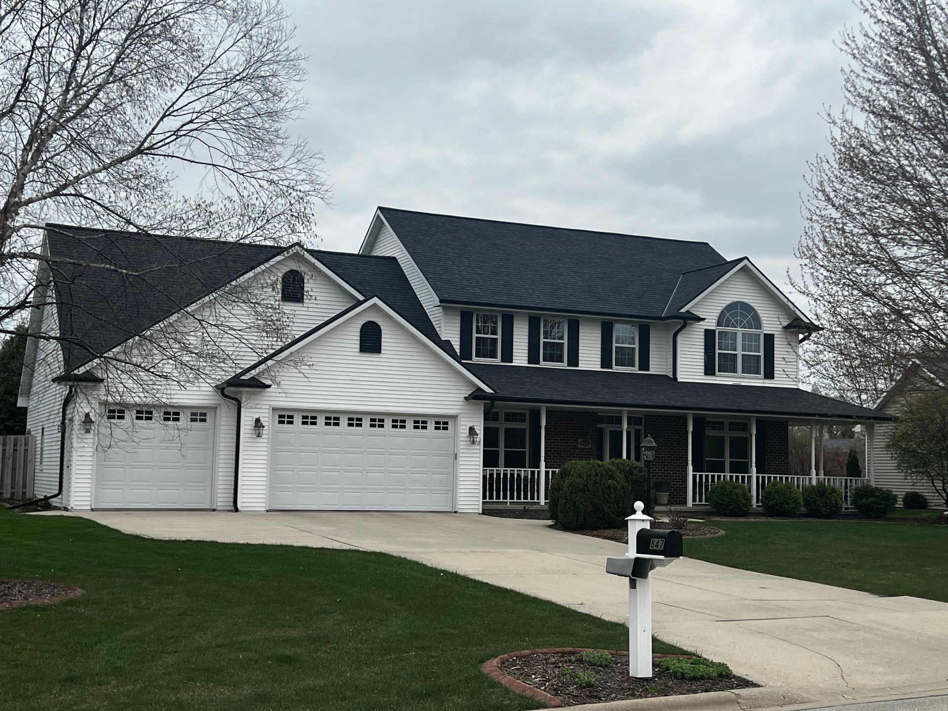 A large white house with a black roof and white garage doors